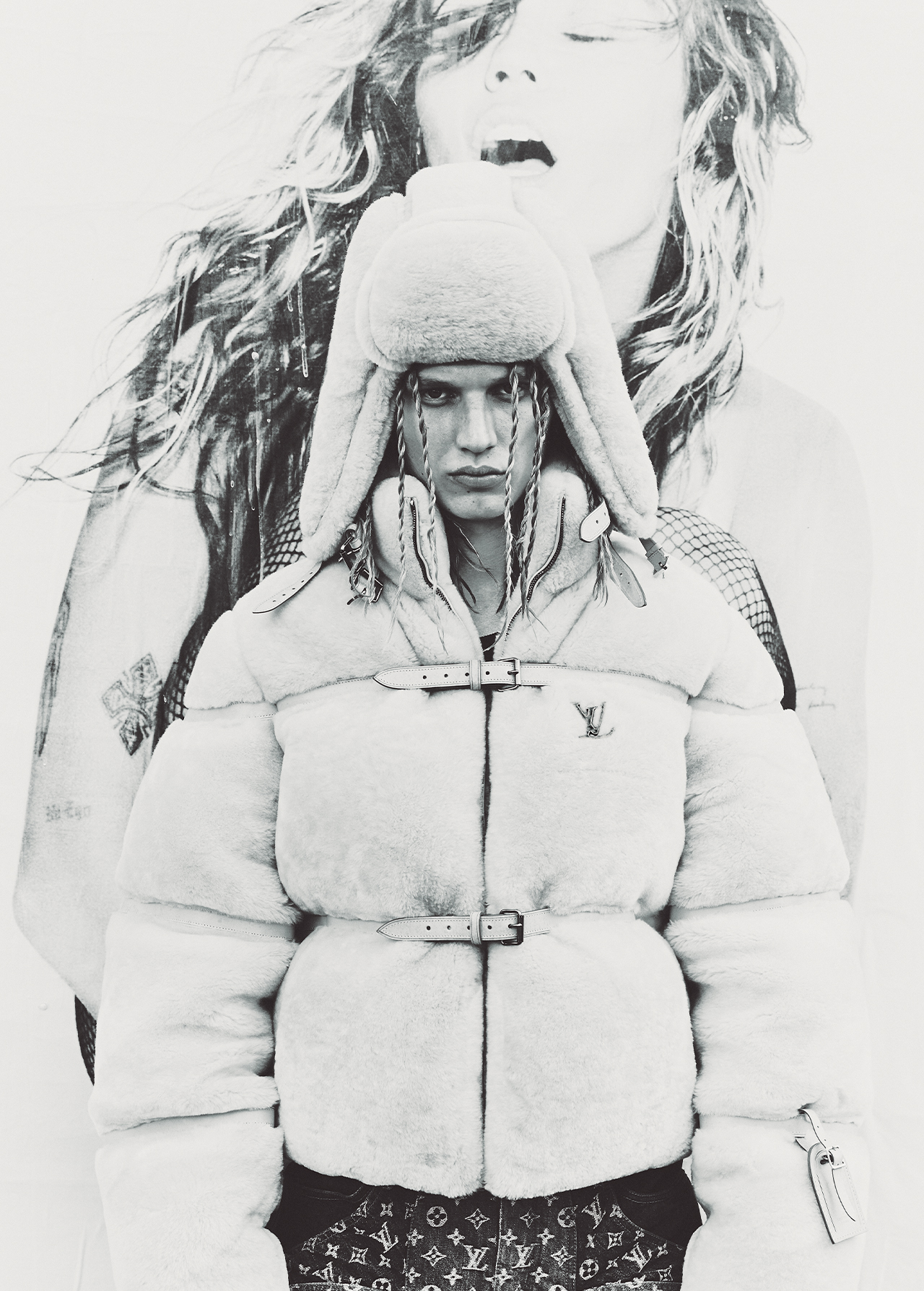 Monochrome fashion shot of a woman in a faux fur jacket and hat, set against a large portrait of a woman with flowing hair.