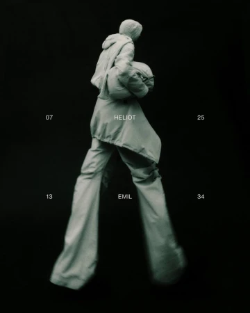 Person walking in loose fitting hooded jacket and pants against dark background, studio shot, fashion concept, muted tones.