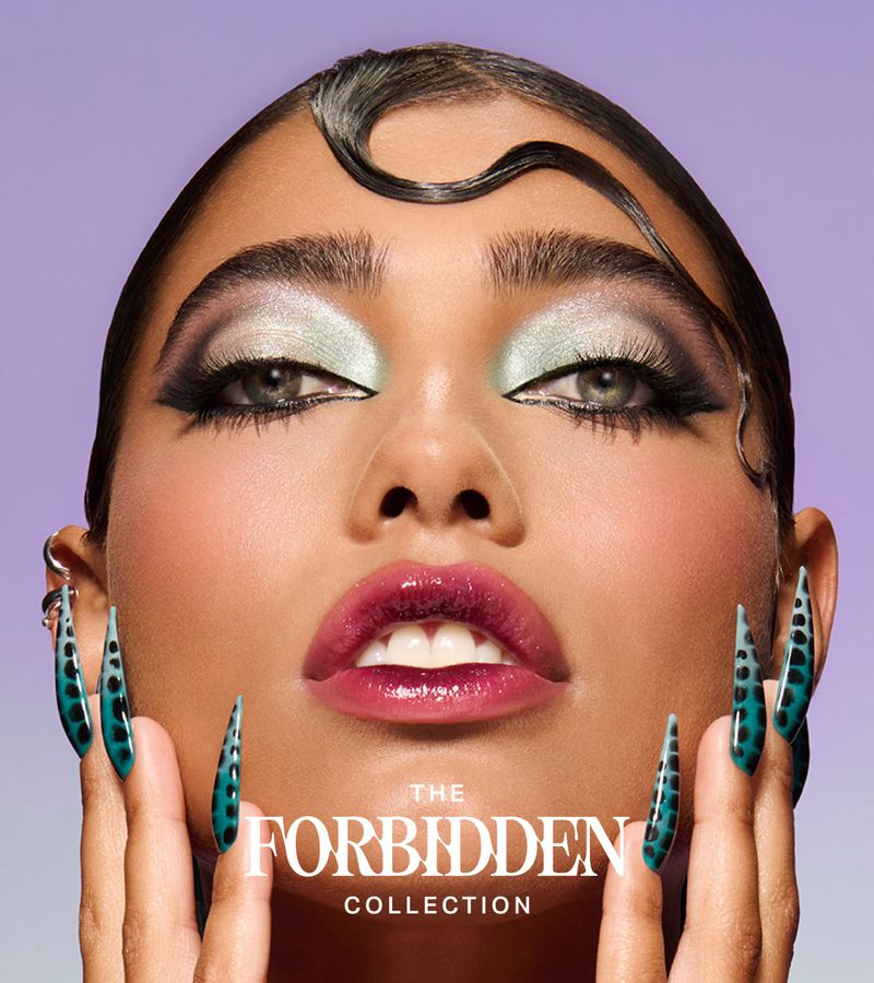 Beauty shot of an adult female with extravagant eye makeup and glossy lips, enhanced by strikingly long, spotted nails on a light purple backdrop.