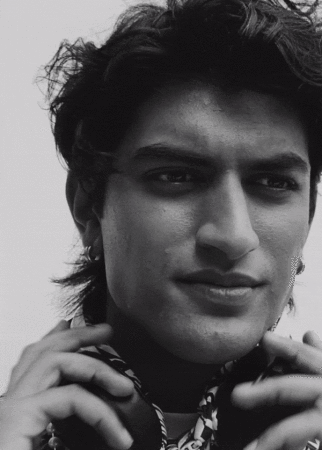 Close-up monochrome portrait of a young man holding headphones against a plain light background
