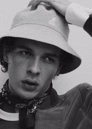Close-up portrait of a man wearing a bucket hat and patterned neck scarf from the Waiting Room project by Justin Woo.