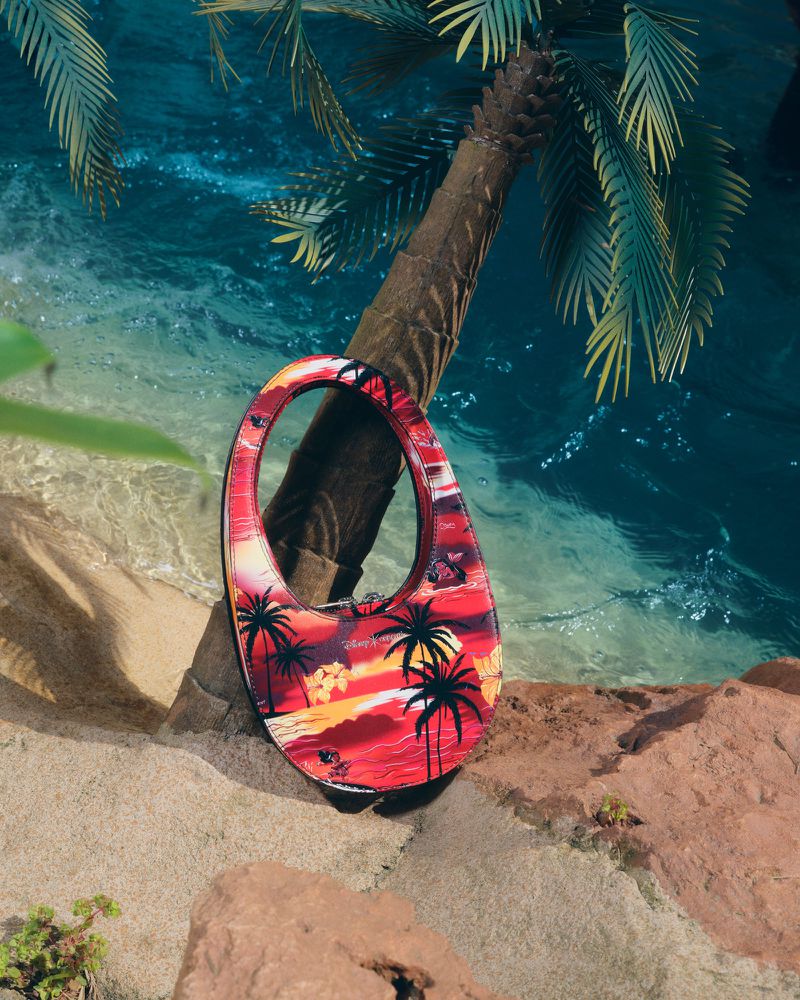 Fashionable handbag featuring tropical beach scene with palm trees against an ocean and sand background for a vibrant, summery aesthetic.