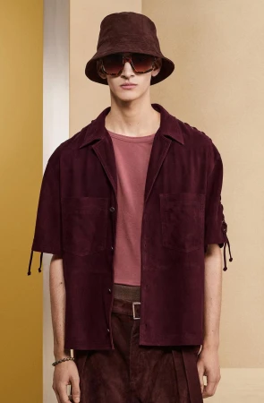 A stylish adult male in brown coordinates poses indoors, wearing a bucket hat and sunglasses, creating a fashion-forward aesthetic.