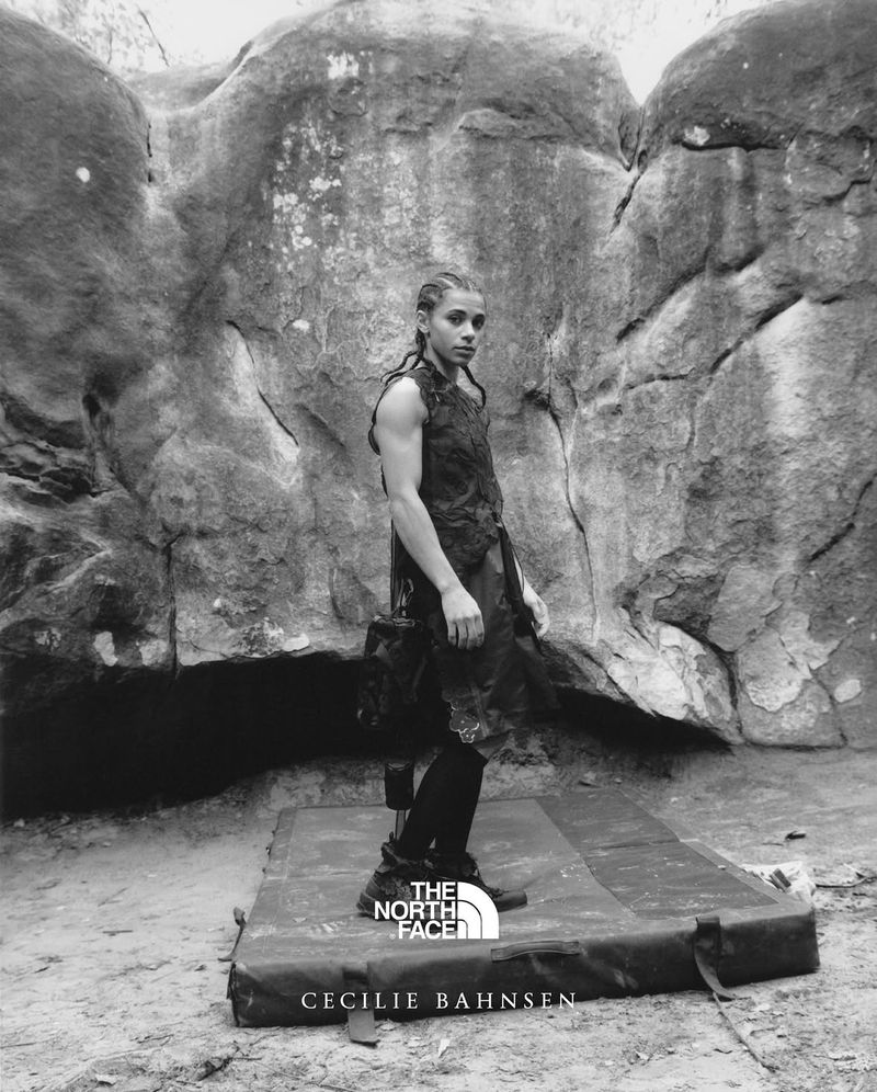 Monochrome portrait of a woman standing outdoors near rock formations wearing a sleeveless dress, logo visible for The North Face.