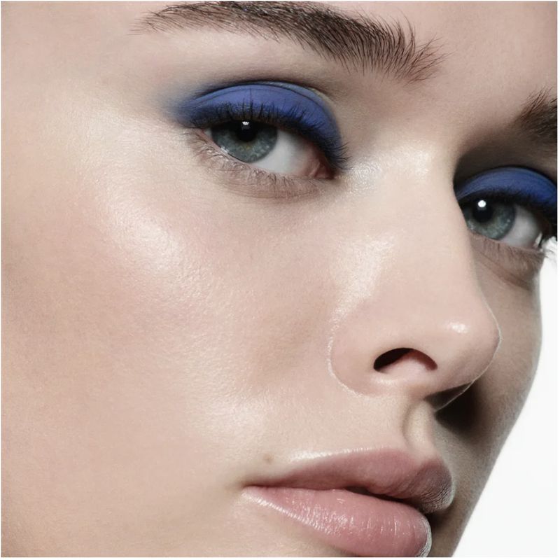 Close-up shot of a woman's face with striking blue eyeshadow, highlighting her eyes and fair skin in a beauty-focused composition.