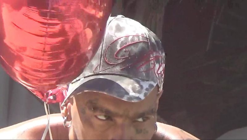 Close-up of a person wearing a cap with a red balloon in the foreground, showcasing a unique and captivating portrait.