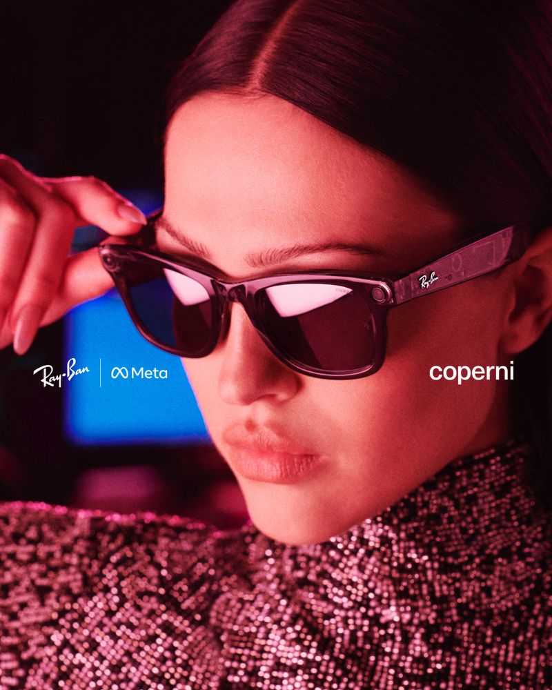 Portrait of a woman wearing Ray-Ban Meta smart glasses, with a sequined top and a backdrop featuring brand logos and 'coperni' text.