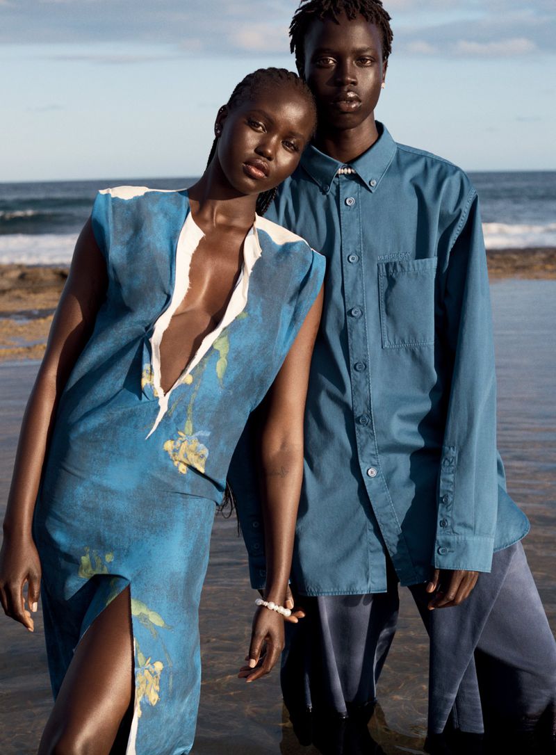 Adut Akech and Bior Akech posing outdoors by the ocean in blue apparel for Vogue Australia shot by Josh Olins.