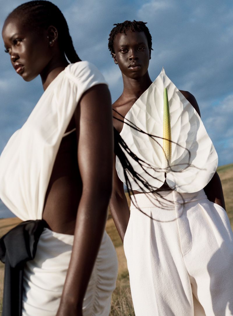 Two black fashion models posing outdoors against a blue sky, wearing white garments in an editorial shoot for Vogue Australia.