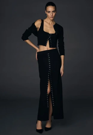 Emm Arruda modeling a black coordinated knit set for the Victoria's Secret and Altuzarra collection against a dark grey seamless backdrop.
